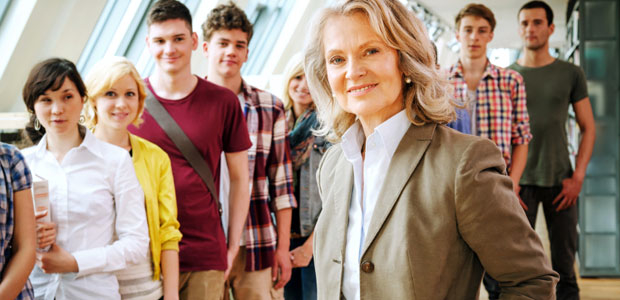 ZAPS supplements classroom instruction with helpful test-taking strategies. A woman principal stands in a hallway smiling at the camera with a line of high school students nearby.