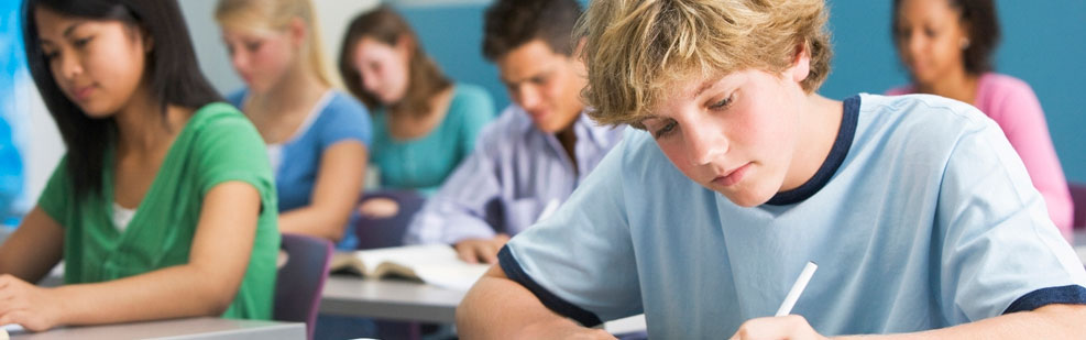 A teenage boy takes notes in a ZAPS PSAT seminar.