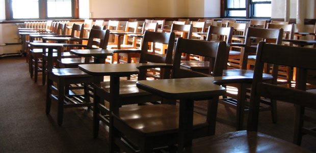 Classrooms like this will soon be filled with high school students taking a ZAPS seminar. Contact us today to make that happen on your campus. An empty classroom has several rows of old, wooden one-armed desk/chairs. The room is bathed in sunlight from the windows.